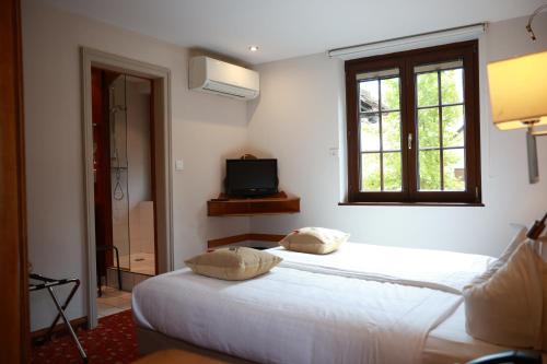 a bedroom with two white beds and a window at Hotel - Restaurant Le Cerf & Spa in Marlenheim