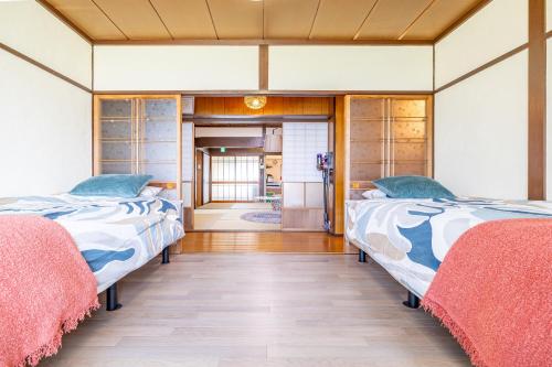 two beds in the middle of a room at Lax奈良 奈良観光に便利な和モダン古民家 最大12名 グループや家族旅行に最適 in Nara