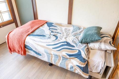 a bed with a blanket on it in a room at Lax奈良 奈良観光に便利な和モダン古民家 最大12名 グループや家族旅行に最適 in Nara