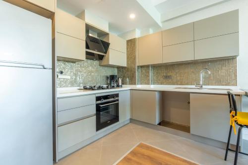 a kitchen with white cabinets and a refrigerator at Cozy Stay Free Pool Spa & Gym Close to Beach&Mall in Lara