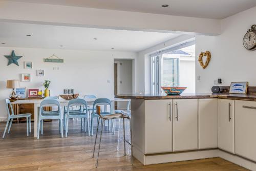 eine Küche und ein Esszimmer mit weißen Schränken und blauen Stühlen in der Unterkunft Sundowner - West Wittering in East Wittering