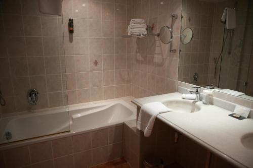 a bathroom with a tub and a sink and a bath tub at Hotel - Restaurant Le Cerf & Spa in Marlenheim
