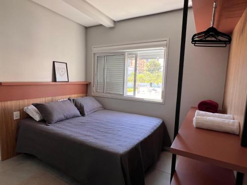 a small bed in a room with a window at Charmoso apê, perto da faculdade e da gastronomia in Passo Fundo