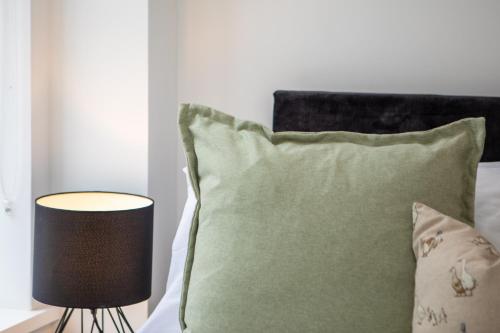 a bed with a green pillow and a lamp at St James Court Hotel in Derby