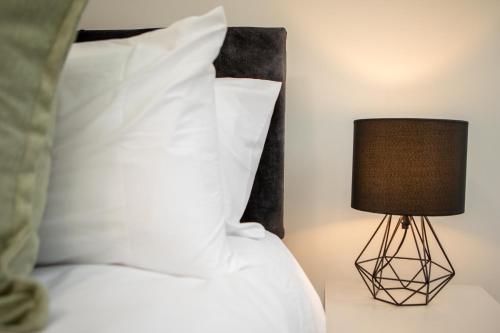 a bed with a white pillow and a lamp at St James Court Hotel in Derby