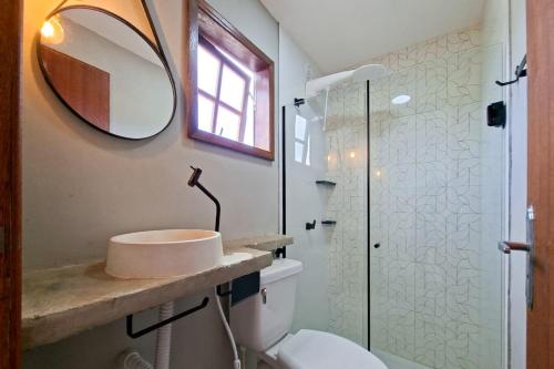 a bathroom with a sink and a toilet and a mirror at Suíte casal in Arraial do Cabo