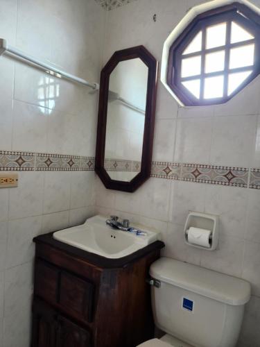 a bathroom with a sink and a toilet and a mirror at Kaisers Sunset Hotel - Adults Only, Negril in Negril