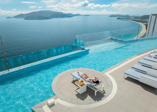 a woman laying in a chair next to a swimming pool at MAISON SEAFRONT RESIDENCE Nha Trang in Nha Trang