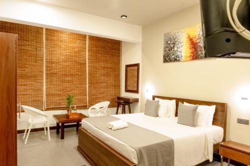 a hotel room with a bed and a table and chairs at Villa Sarungal Kanda in Bandarawela