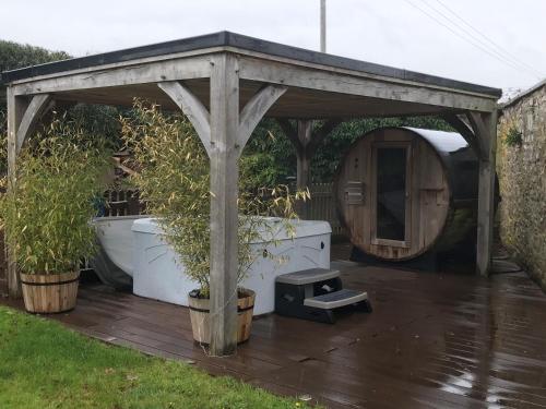 a wooden gazebo with a stove and potted plants at North Lodge at Pudleston Court in Hatfield