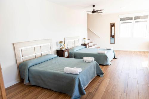 two beds in a room with wooden floors at Casa rural DOS ENCINAS in Andújar