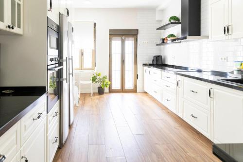 a kitchen with white cabinets and a wooden floor at Casa rural DOS ENCINAS in Andújar