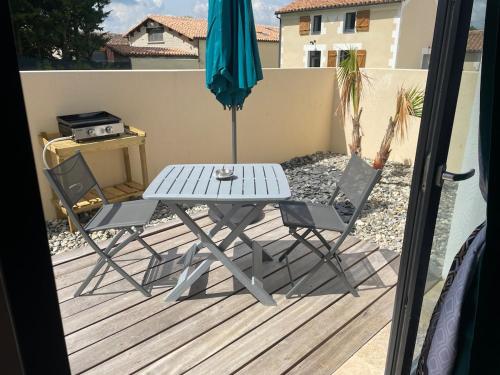 a table and two chairs and an umbrella on a deck at Love room in Paizay-le-Chapt