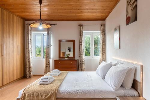 una habitación con una cama grande con sábanas y almohadas blancas en Serenity Paxos, en Gáios