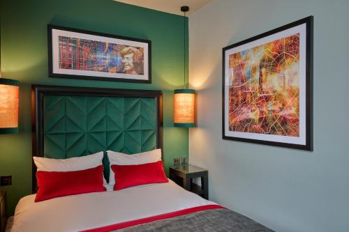 a bedroom with a bed with red pillows and two pictures at Malmaison Manchester in Manchester