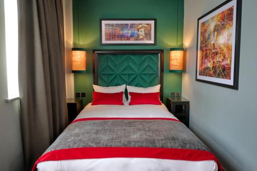 a bedroom with a bed with red pillows and green walls at Malmaison Manchester in Manchester