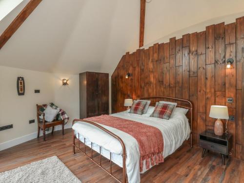 Un dormitorio con una cama y una pared de madera. en Y Cwlwm - The Celtic Knot, en Cribyn