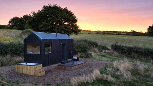 a black tiny house in the middle of a field at Polaris in Kelsall