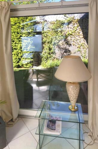 a lamp on a glass table in front of a window at Apartment with terrace in Zeuthen