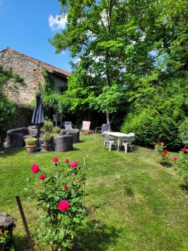 a garden with a table and chairs and roses at Les Volets Bleus in Pointis-Inard