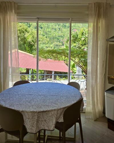 a dining room table with chairs and a large window at Le Voile de la Mariée in Salazie