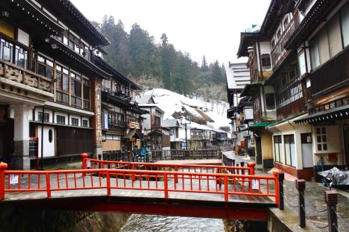a bridge over a river in a town with buildings at Tomaru細野 in Nobezawa