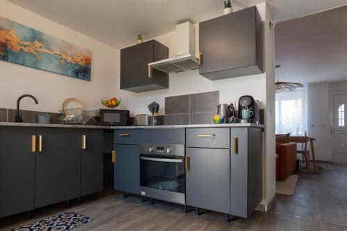 a kitchen with gray cabinets and a stove at La maison du jeu cnpe hypercentre plage 8pers jeux video et de société in Gravelines
