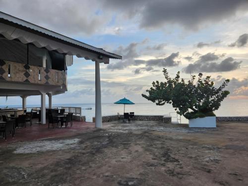 a restaurant with tables and an umbrella on the beach at Kaisers Sunset Hotel - Adults Only, Negril in Negril