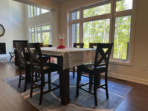ein Esszimmer mit einem Tisch mit Stühlen und Fenstern in der Unterkunft 3000SF Modern Cottage Algonquin, Muskoka 4 bedrooms 6 beds3 baths in Lake of Bays