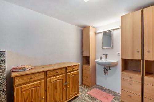 a bathroom with wooden cabinets and a sink at Ferienwohnung Karl-Heinz in Maar