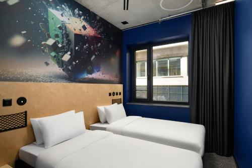 two beds in a room with a painting on the wall at JO&JOE Budapest in Budapest