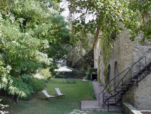 two chairs and an umbrella in a yard next to a building at Ferienwohnung Il Fienile In Umbertide in Umbertide