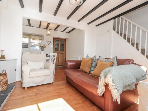 un salon avec un canapé et une chaise dans l'établissement Honeysuckle Cottage, à Oswaldkirk