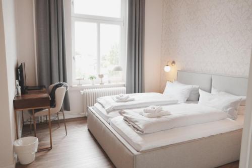 a bedroom with two beds and a desk and a window at Lexow - Hotel an de Havenkant in Tönning