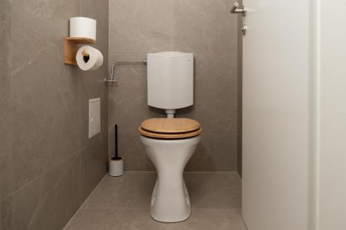 a bathroom with a white toilet with a wooden seat at Wellness Retreat for 2 with Private Sauna & Whirlpool - Free Parking, Quiet City Center by HERO HOMES in Graz