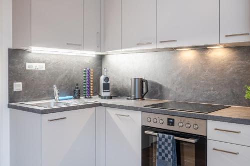 a kitchen with white cabinets and a stove and a sink at Wellness Retreat for 2 with Private Sauna & Whirlpool - Free Parking, Quiet City Center by HERO HOMES in Graz