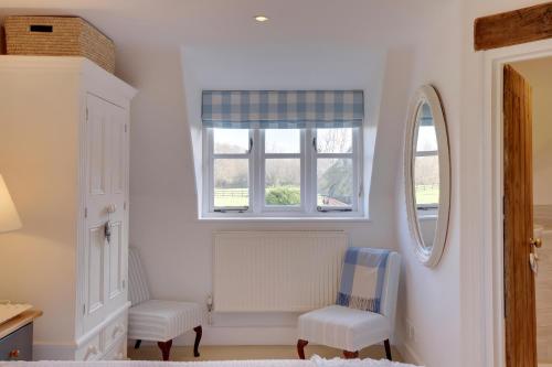 a bedroom with two chairs and a window at Lake Cottage in Swindon