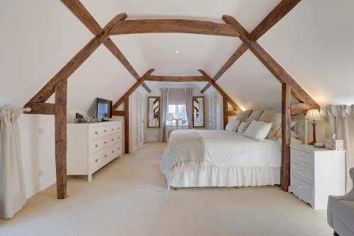 a bedroom with a white bed and wooden beams at Lake Cottage in Swindon