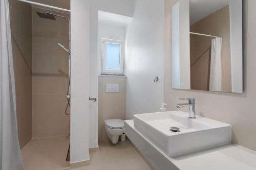 een witte badkamer met een wastafel en een toilet bij Peace House Lourinhã in São Bartolomeu