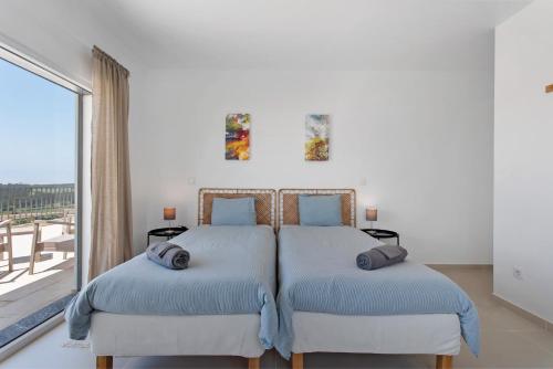2 bedden in een slaapkamer met een groot raam bij Peace House Lourinhã in São Bartolomeu