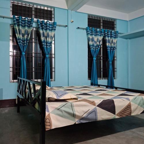 a bedroom with a bed with blue walls and blue curtains at Atithi Homestay in Sivasagar