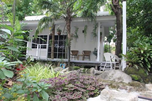 a white house with two chairs in a garden at Homeku Guesthouse Room 4 Cozy Stay Close to Suvarnabhumi Airport in Lat Krabang