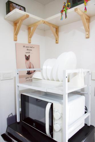 a kitchen with white shelves and a microwave at Homeku Guesthouse Room 4 Cozy Stay Close to Suvarnabhumi Airport in Lat Krabang