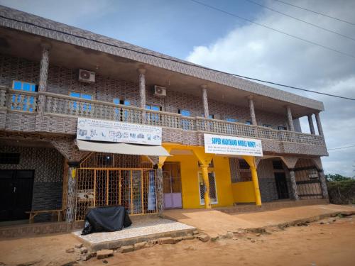 a yellow building with a balcony on the side at Tokpa Dome Appart Garden 