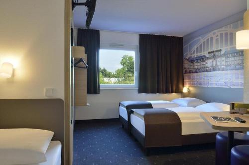 a hotel room with two beds and a window at B&B Hotel Mannheim-Neuostheim in Mannheim