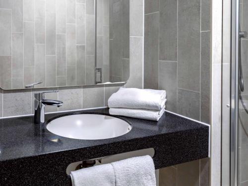a bathroom with a sink and a mirror at B&B Hotel Mannheim-Neuostheim in Mannheim