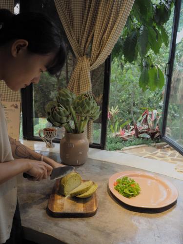 Una mujer cortando un sándwich en una tabla de cortar con un cuchillo. en Hè Maison Retreat, en Teurnoum