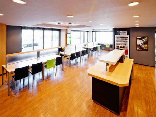 a cafeteria with tables and chairs in a building at Super Hotel Minamata in Minamata