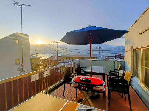 a balcony with a table and an umbrella at 1日1組貸切網代の風 in Atami