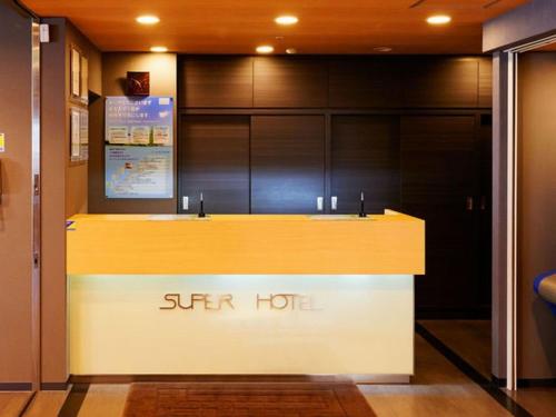 a reception desk in a building with a sign on it at Super Hotel Minamata in Minamata